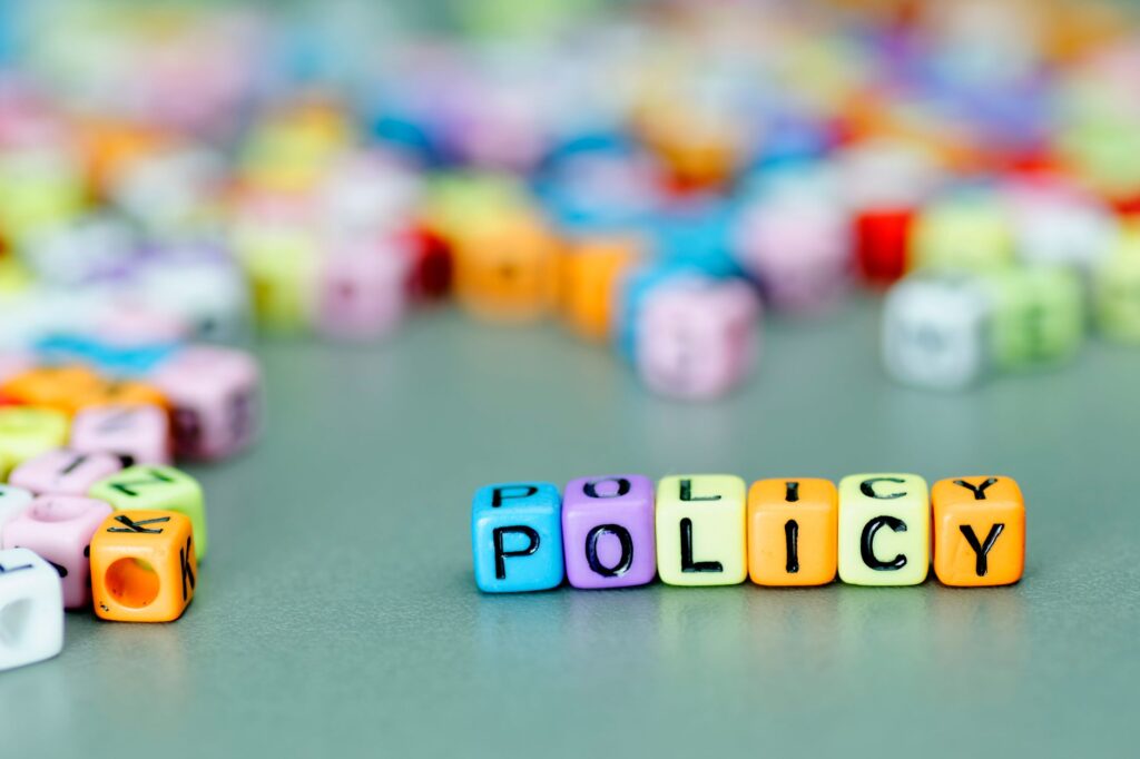 Colorful letter blocks spell out "POLICY," subtly echoing a Cyber Resilience Strategy against a blurred background of scattered blocks.