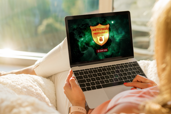 A lady holding a laptop with Antivirus protection symbol on screen.