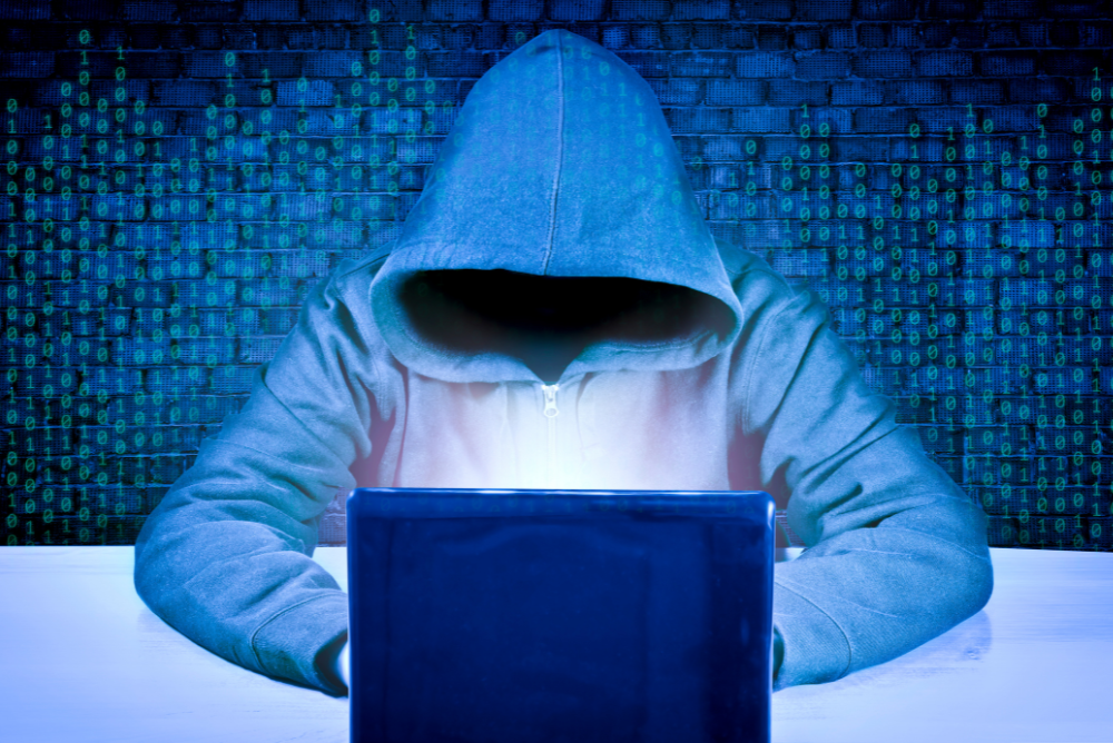 A faceless hacker in front of a laptop.