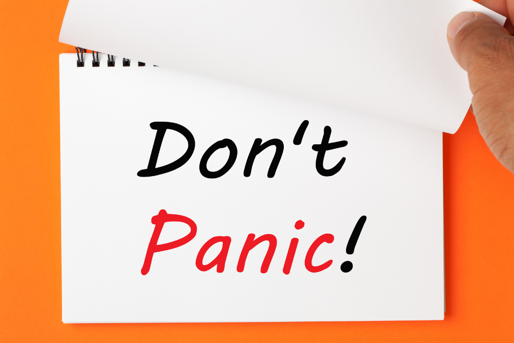 Don't panic! written on a white note against an orange background.